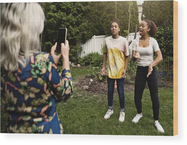 Diversity Wood Print featuring the photograph Mixed-race sisters being filmed by mother in backyard. #1 by Martinedoucet