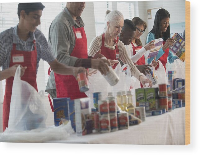Asian And Indian Ethnicities Wood Print featuring the photograph Volunteers packing canned goods at food drive #1 by Jose Luis Pelaez Inc