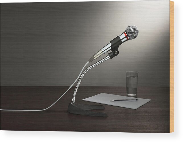 Empty Wood Print featuring the photograph A microphone in a stand, with paper and a glass of water, all on a wooden desktop by Creative Crop