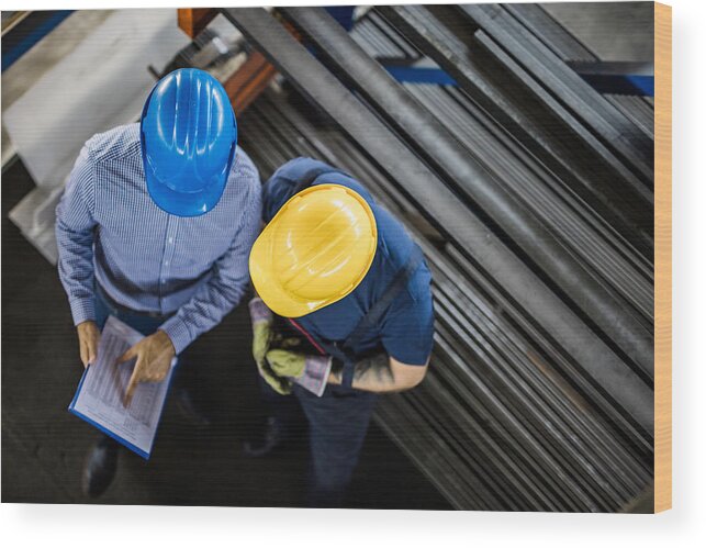 Metallurgy Wood Print featuring the photograph Above view of manager and manual worker reading reports in steel mill. by Skynesher