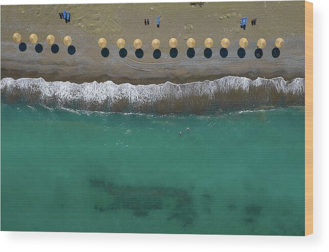  Beach Wood Print featuring the photograph Aerial view from a flying drone of beach umbrellas in a row on a by Michalakis Ppalis