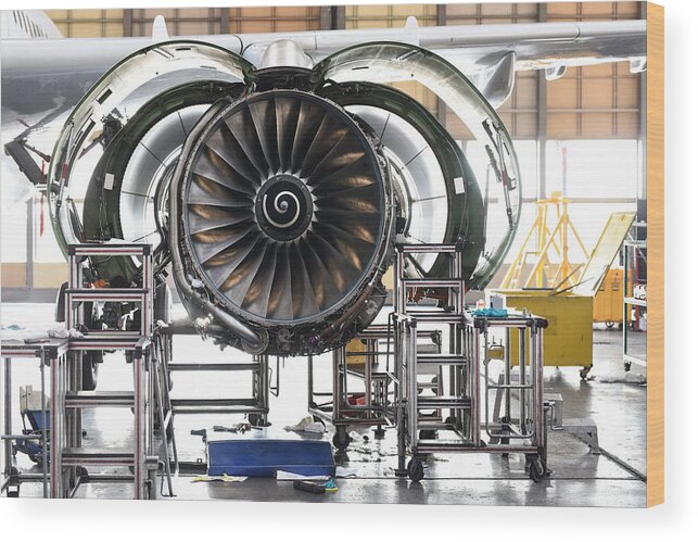 Manufacturing Equipment Wood Print featuring the photograph Aircraft Jet engine maintenance in airplane hangar by Baranozdemir