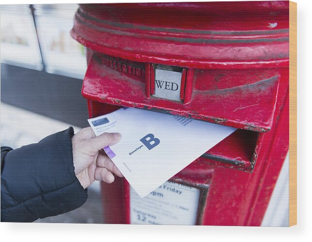 Democracy Wood Print featuring the photograph British Postal voting envelop is being dropping into a postbox by Sunphol Sorakul
