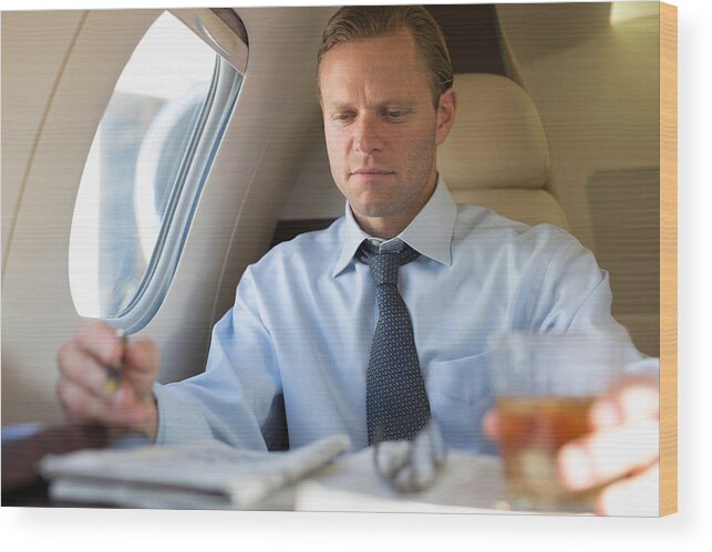 People Wood Print featuring the photograph Businessman doing crossword on airplane by Image Source/InStock