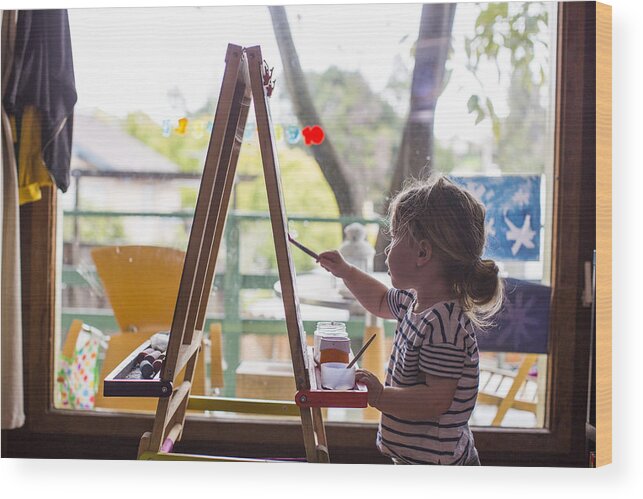 Toddler Wood Print featuring the photograph Caucasian girl painting on easel near window by Adam Hester