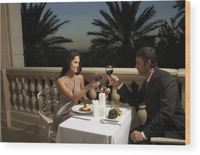 Heterosexual Couple Wood Print featuring the photograph Couple in evening wear having dinner on balcony, toasting with red wine by Andrea Chu