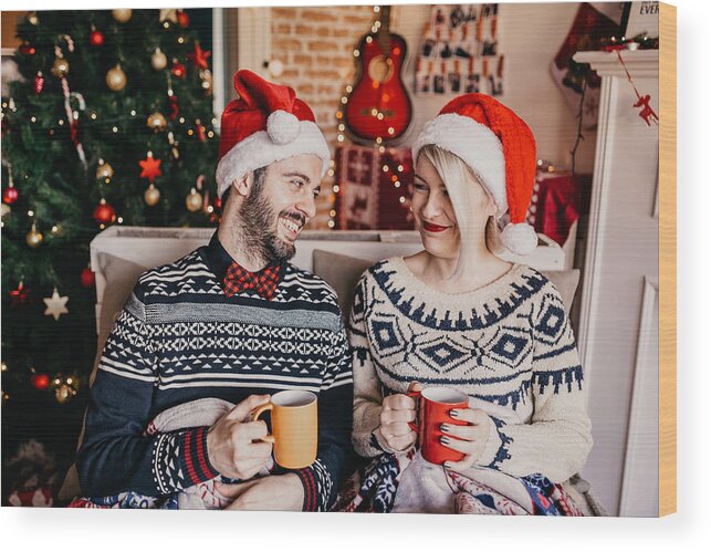 Hipster Wood Print featuring the photograph Couple relaxing and drinking tea in front of a Christmas tree by Anchiy