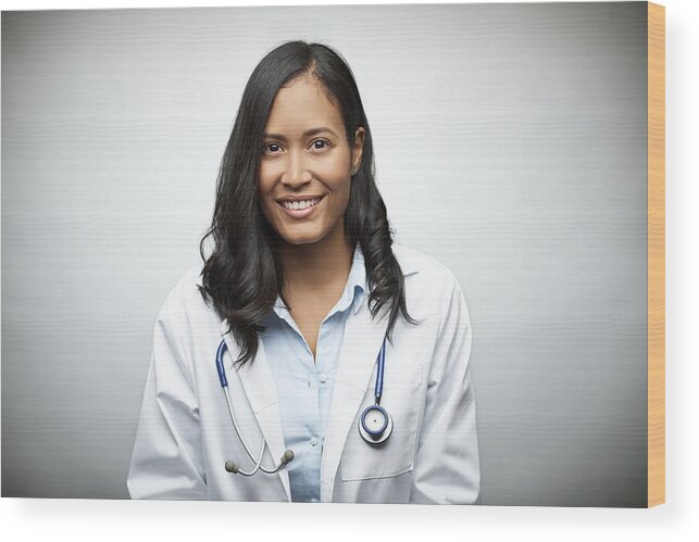 Expertise Wood Print featuring the photograph Female doctor smiling over white background by Morsa Images
