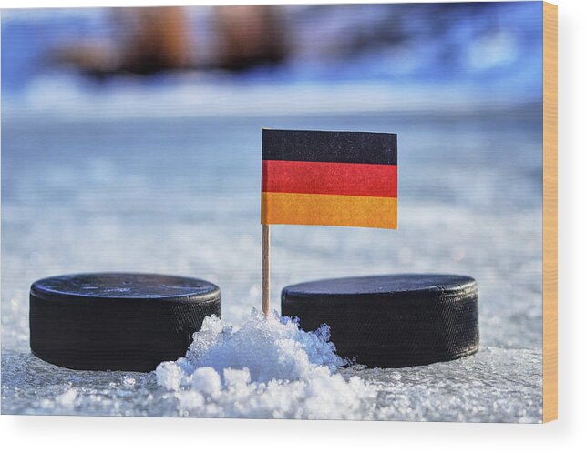 Germany Wood Print featuring the photograph Germany flag on toothpick between two hockey pucks. Winter classic. Flag on frozen pond on unkempt ice. Traditional pucks for international matches. by Vaclav Sonnek