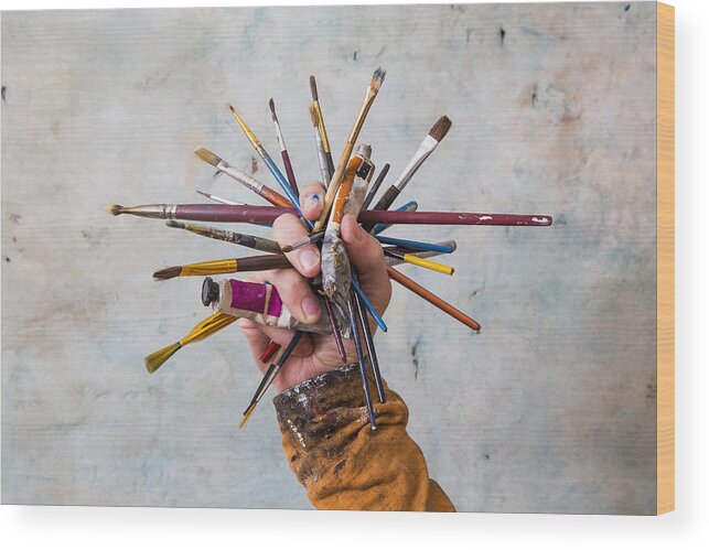 Artist Wood Print featuring the photograph Hand holding cluster of paint brushes and paints by Dimitri Otis
