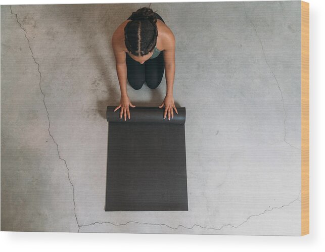 Tranquility Wood Print featuring the photograph High angle view of a young adult woman closing a yoga mat by FilippoBacci