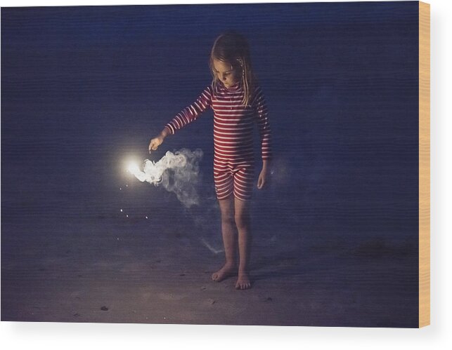 4-5 Years Wood Print featuring the photograph Little girl playing with bengal fire on the beach at dusk. by Martinedoucet