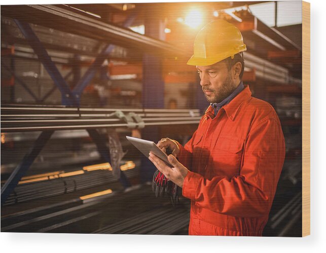 Mid Adult Wood Print featuring the photograph Manual worker using digital tablet in industrial building. by BraunS