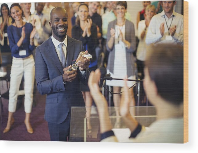 Convention Center Wood Print featuring the photograph Portrait of young man holding trophy, standing in conference room, smiling to applauding audience by Caiaimage/Paul Bradbury