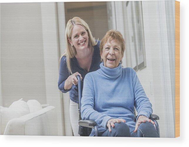 Retirement Wood Print featuring the photograph Senior woman in wheelchair with caregiver at home by Kali9