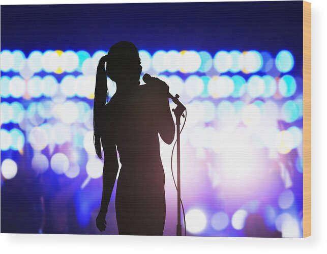 Cool Attitude Wood Print featuring the photograph Silhouette of woman with microphone singing on concert stage in front of crowd by FangXiaNuo
