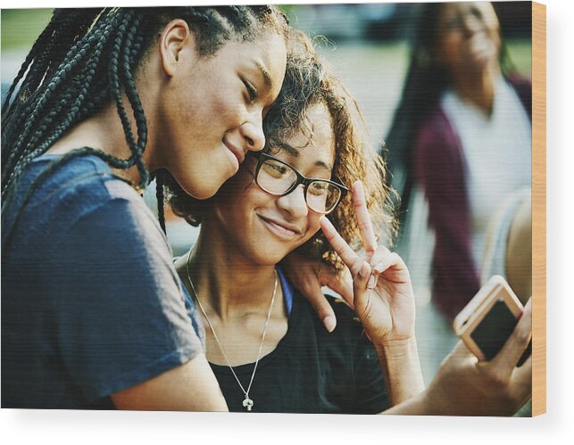 Tranquility Wood Print featuring the photograph Smiling teenage friends taking selfie with smartphone on summer evening by Thomas Barwick