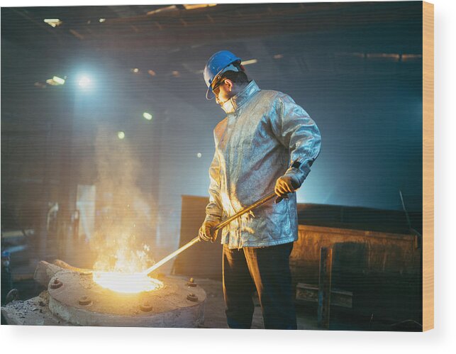 Working Wood Print featuring the photograph Steel worker in protective clothing raking furnace in an industry by RainStar