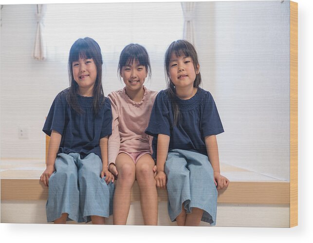Sibling Wood Print featuring the photograph Twin girls sitting together with older sister by Trevor Williams