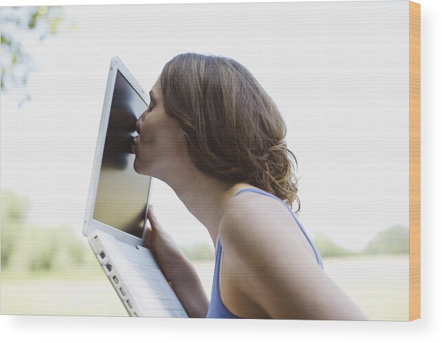 Internet Wood Print featuring the photograph Woman kissing laptop screen outdoors by Tom Merton
