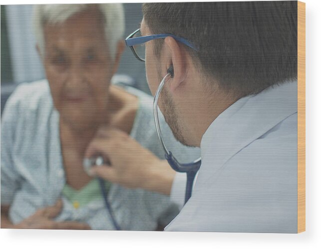 Advice Wood Print featuring the photograph Young doctor listening heartbeat with stethoscope of old woman,Rural medicine concept. by Visoot Uthairam