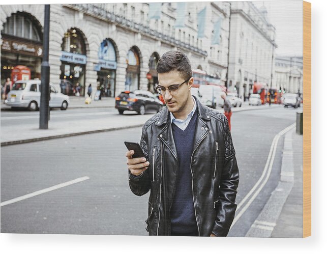 Internet Wood Print featuring the photograph Young man reading from his cell phone on the busy street by Alexander Spatari