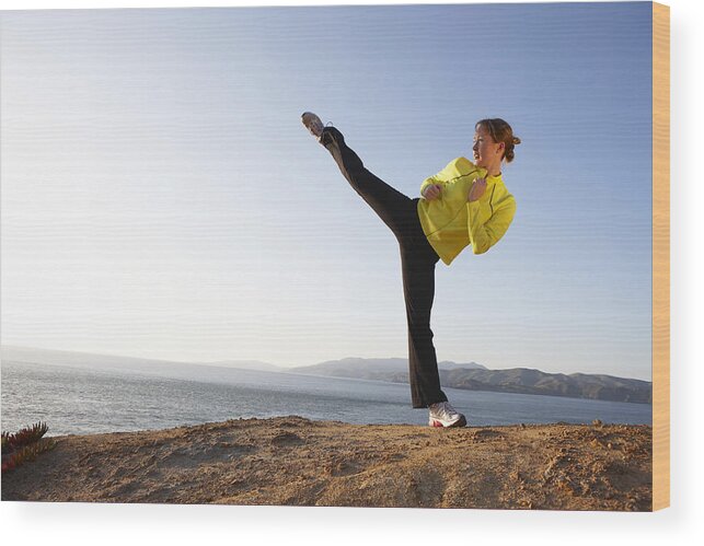 Standing On One Leg Wood Print featuring the photograph Young woman practicing high kick on shore by Marcy Maloy
