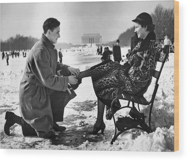 1936 Wood Print featuring the photograph Man Lends A Helping Hand To Put On Skates by Underwood Archives