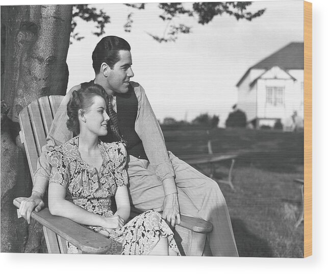Heterosexual Couple Wood Print featuring the photograph Couple Relaxing On Deckchair In Garden by George Marks
