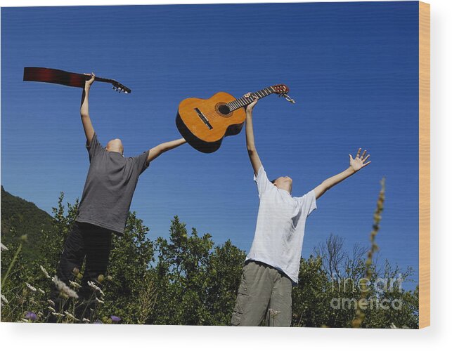 Vitality Wood Print featuring the photograph Two boys standing in meadow holding guitars in outstretched arms by Sami Sarkis