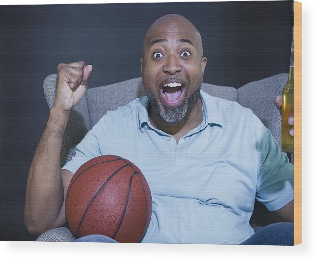 Human Limb Wood Print featuring the photograph African American man drinking beer and watching basketball on television by JGI/Jamie Grill