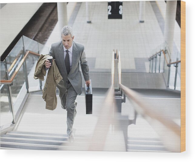 Mature Adult Wood Print featuring the photograph Businessman walking up stairs in train station by Paul Bradbury