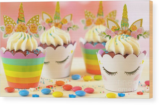 Cupcake Wood Print featuring the photograph Decorating children's birthday party unicorn themed cupcakes, closeup. by Milleflore Images