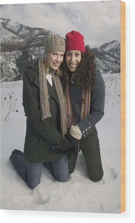 Snow Wood Print featuring the photograph Full Length Shot Of Two Young Adult Women In Winter Clothing As They Both Kneel Down In The Snow by Photodisc