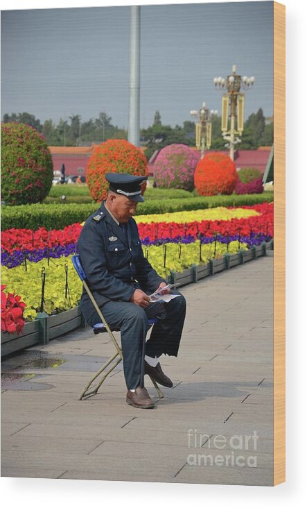 Guard Wood Print featuring the photograph Chinese security guard reads in front of flower display Beijing China by Imran Ahmed