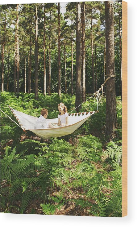 Hanging Wood Print featuring the photograph Boy And Girl 8-10 Sitting On Hammock In by Martin Barraud