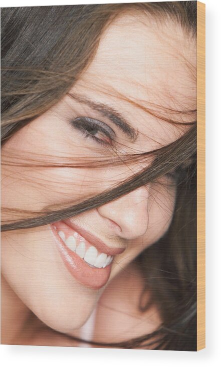Caucasian Ethnicity Wood Print featuring the photograph Close Up Of A Young Attractive Caucasian Brunette Who Smile Into The Camera As Her Hair Is Tossed In Front Of Her Face by Digital Vision
