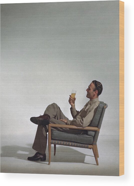 Fine Art Wood Print featuring the photograph A Man Sitting In An Armchair With A Drink by John Rawlings