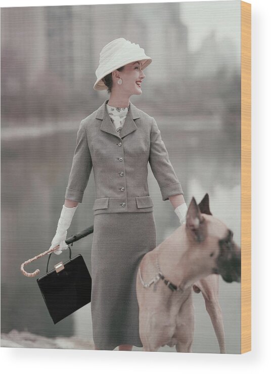 Fashion Accessories Animal Outdoors Daytime Front View One Person People Female Model Young Woman Young Adult Young Adult Woman Looking Away One Animal Animals Dog Domesticated Animal Pet Smiling Hat Headgear Purse Bag Blazer Jacket Skirt Gloves Umbrella Glamour Great Dane 1950s Style 20-24 Years 20s Adult #condenastvoguephotograph February 1st 1956 Wood Print featuring the photograph A Model Wearing A Gray Suit With A Dog by Karen Radkai