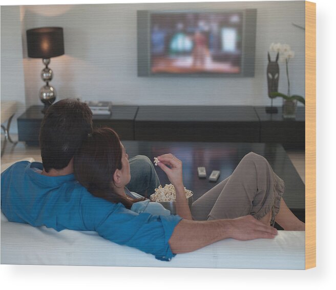 Young Men Wood Print featuring the photograph Couple watching television together and eating popcorn by Chris Ryan