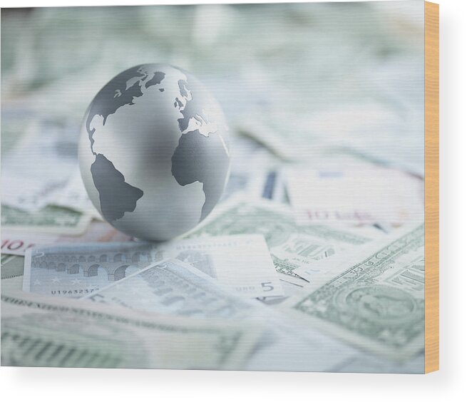 Globe Wood Print featuring the photograph Metal globe resting on paper currency by Martin Barraud