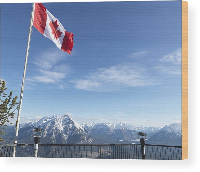 Scenics Wood Print featuring the photograph Canada, Alberta, Banff National Park, Canadian flag blowing above viewing deck, mountain range in background by Ascent/PKS Media Inc.