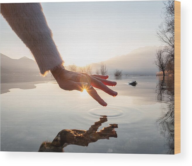 Tranquility Wood Print featuring the photograph Detail of hand touching water surface of lake at sunset by Swissmediavision