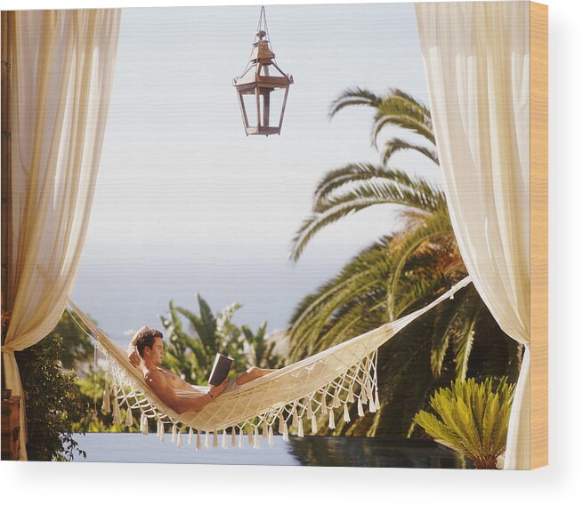 Hands Behind Head Wood Print featuring the photograph Man Lying in Hammock Reading a Book by Flying Colours Ltd