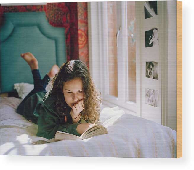 Tranquility Wood Print featuring the photograph Teenage Girl Lying On Her Bed, Reading A Book by Alys Tomlinson