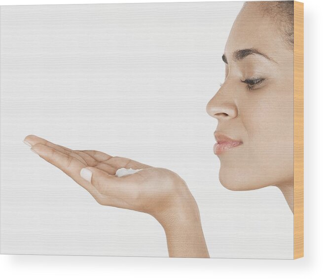 White Background Wood Print featuring the photograph Young woman holding moisturizing cream on palm of hand by Amana Productions Inc.