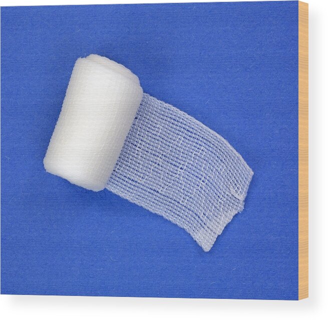 Medical Equipment Wood Print featuring the photograph Roll of first aid gauze unrolling by BWFolsom