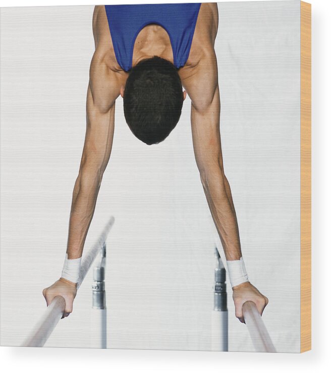 Human Arm Wood Print featuring the photograph Male gymnast performing handstand on parallel bars, upper section, rear view. by Dominique Douieb