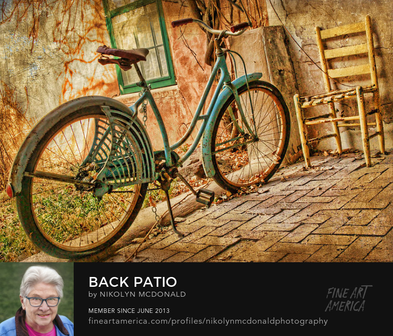 old bicycle and chair behind adobe home by nikolyn mcdonald