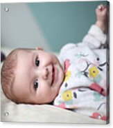 A Baby Girl Smiling On A Bed Acrylic Print